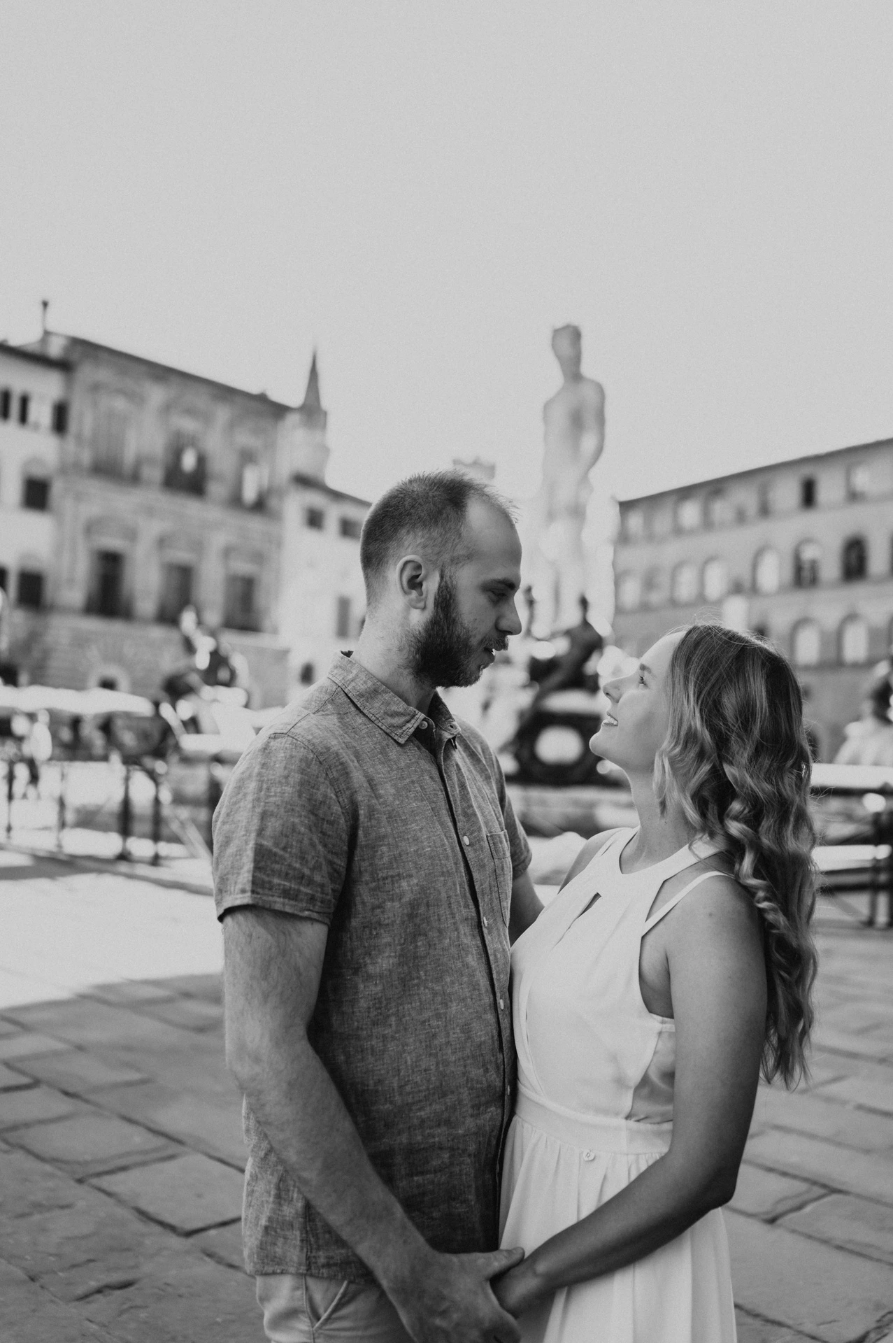 Black-and-white close portrait of the couple facing each other near the Neptune Fountain during their Florence photoshoot.