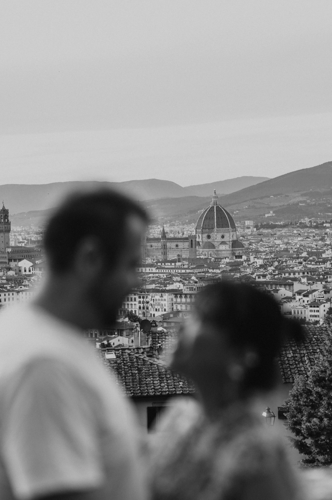 Black-and-white Florence photoshoot with the Duomo in focus behind the softly blurred couple facing one another.