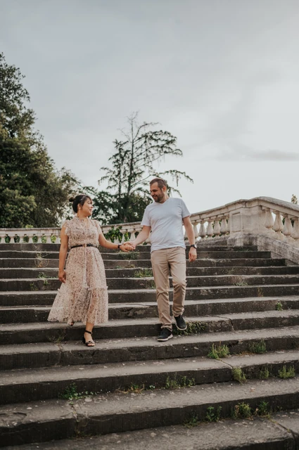 Florence couple photoshoot on the broad stone steps The couple walk down the broad stone steps holding hands during their Florence photoshoot, with the balustrade rising behind them.
