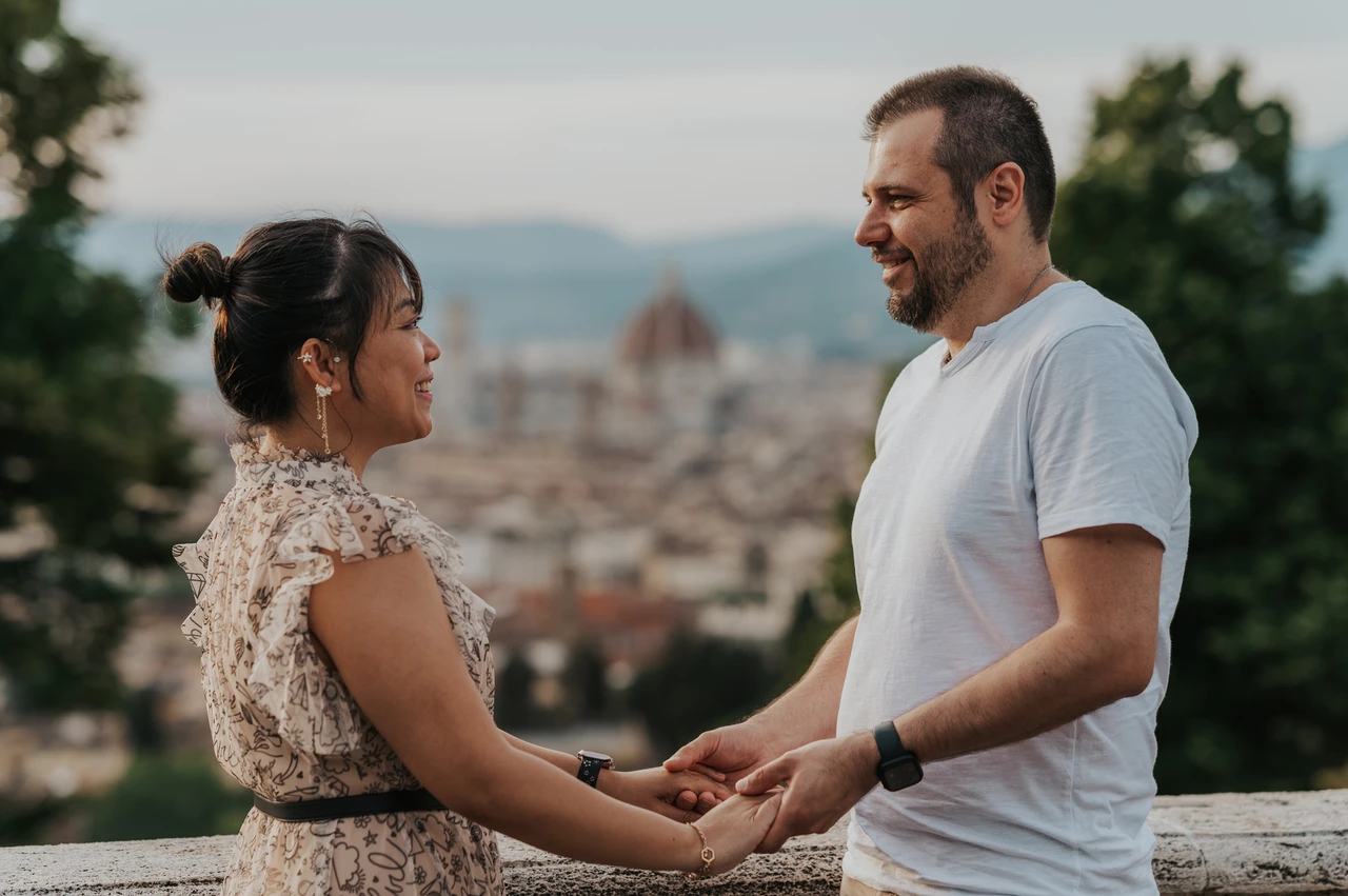 Florence couple photoshoot holding hands above the city The couple hold hands beside the stone balustrade, with Florence and its hills behind them during their couple photoshoot.