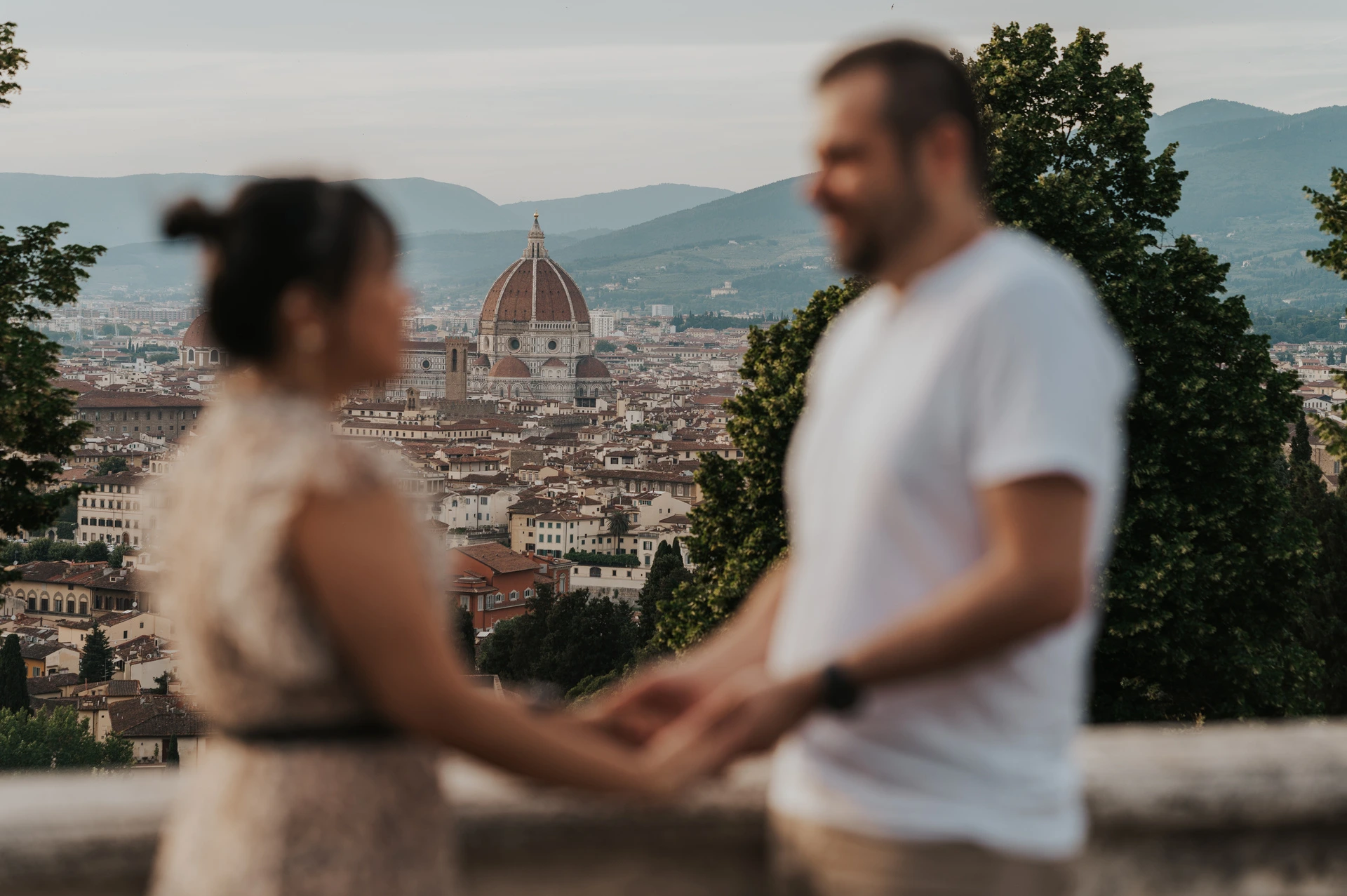 Florence Cathedral is in focus between the softly blurred couple holding hands in the foreground of their Florence photoshoot.