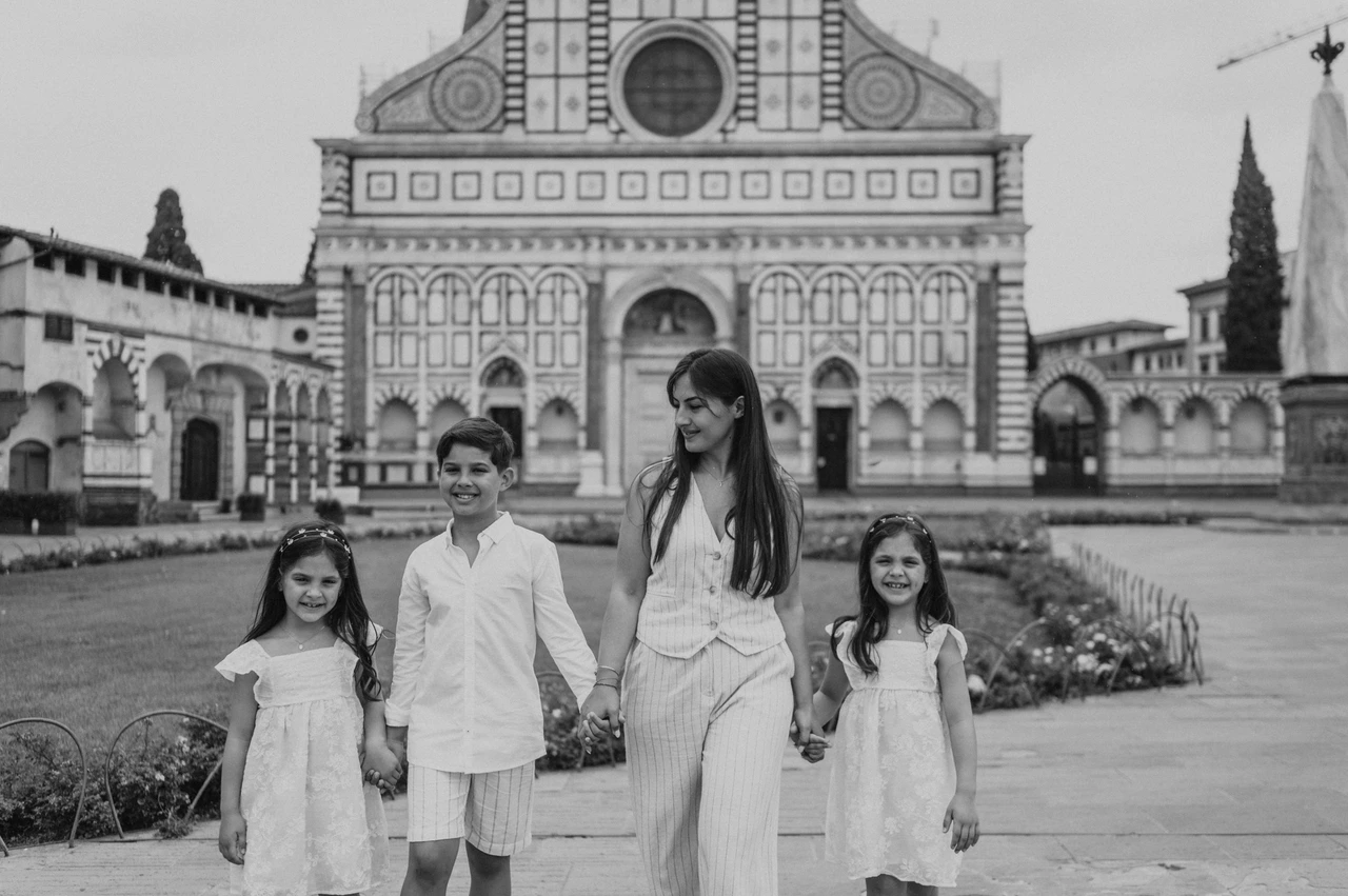 Florence family photoshoot at Santa Maria Novella in black and white Black-and-white photograph of the family holding hands in front of Santa Maria Novella during their Florence family photoshoot.