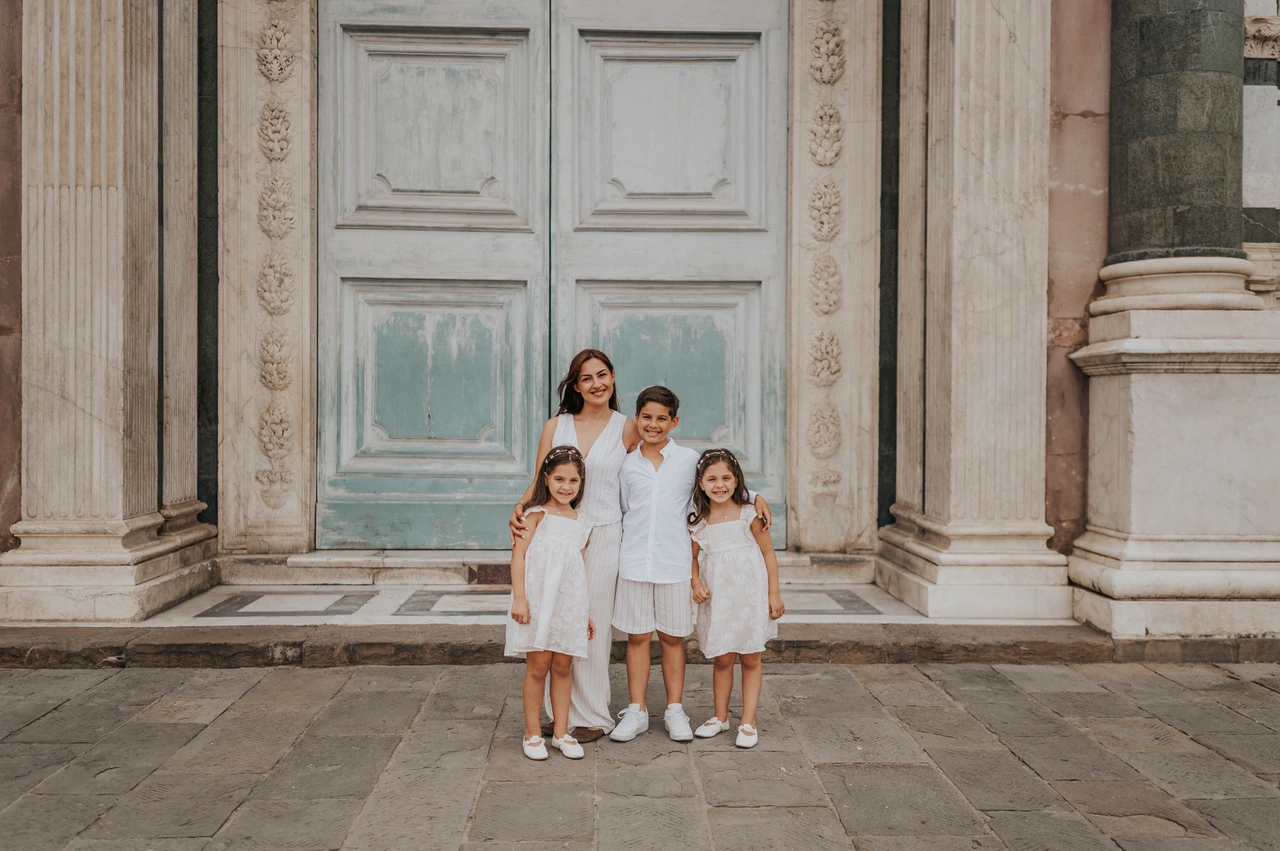 A wide doorway portrait during a Florence family photoshoot Wide photograph of the family standing in front of a pale green door and patterned marble during their Florence photoshoot.