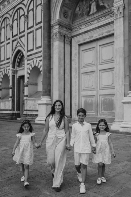 A family walk in black and white during a Florence photoshoot Black-and-white photograph of the family walking together beside the marble entrance during their Florence photoshoot.
