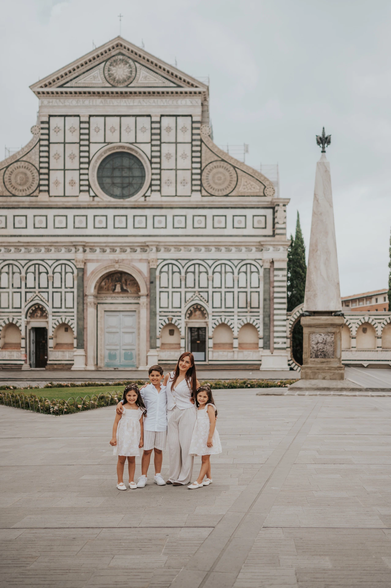 The family stand in the square with Santa Maria Novella’s full marble facade behind them during their Florence photoshoot.