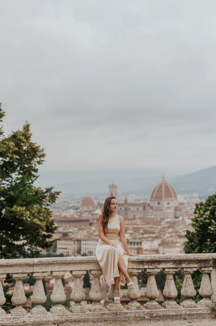 A cream-dress portrait during a Florence proposal photoshoot She sits in a cream dress on the stone balustrade above Florence during the proposal photoshoot.
