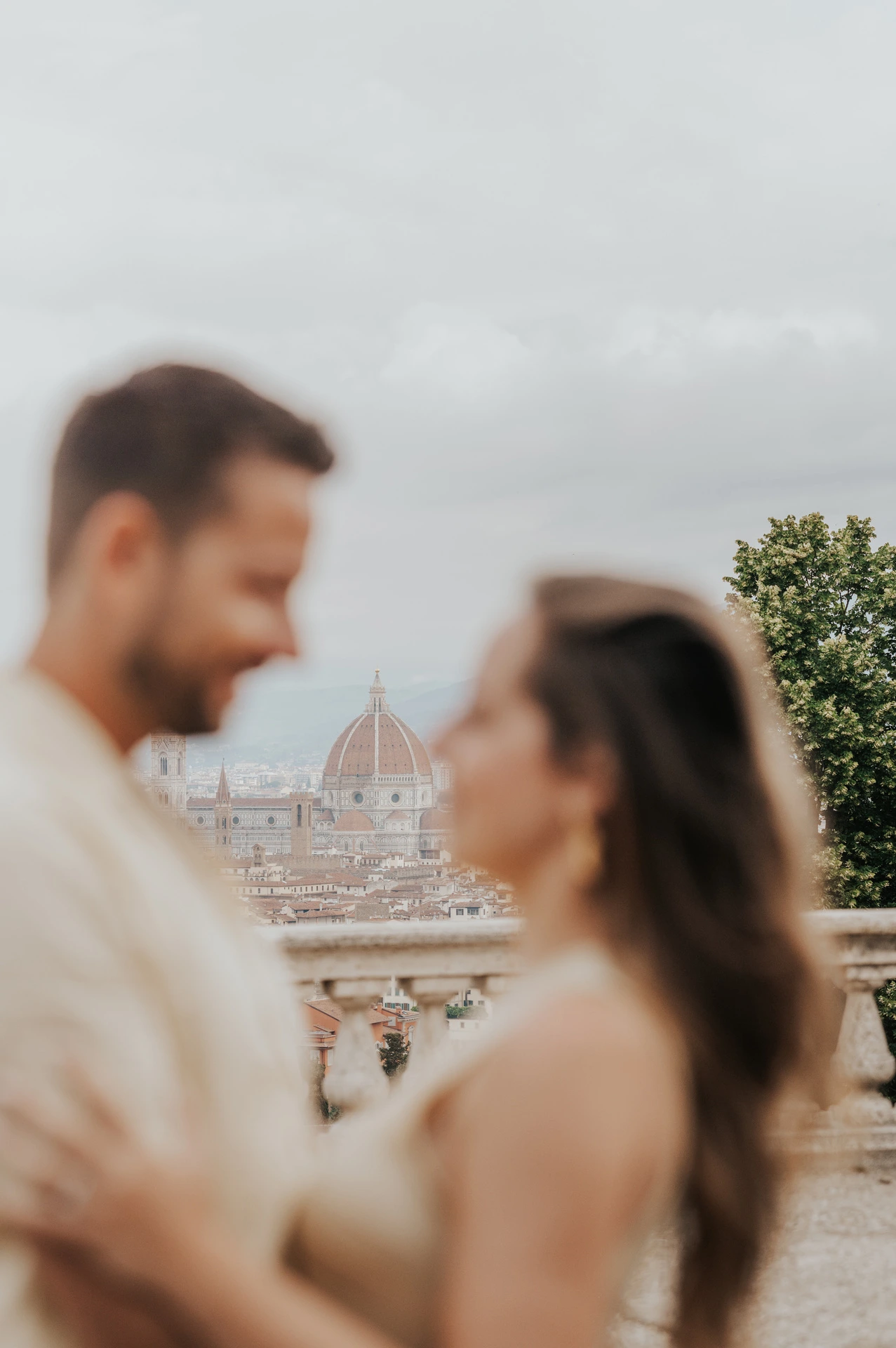 The Duomo appears between the softly blurred couple in a close portrait during their Florence proposal photoshoot.