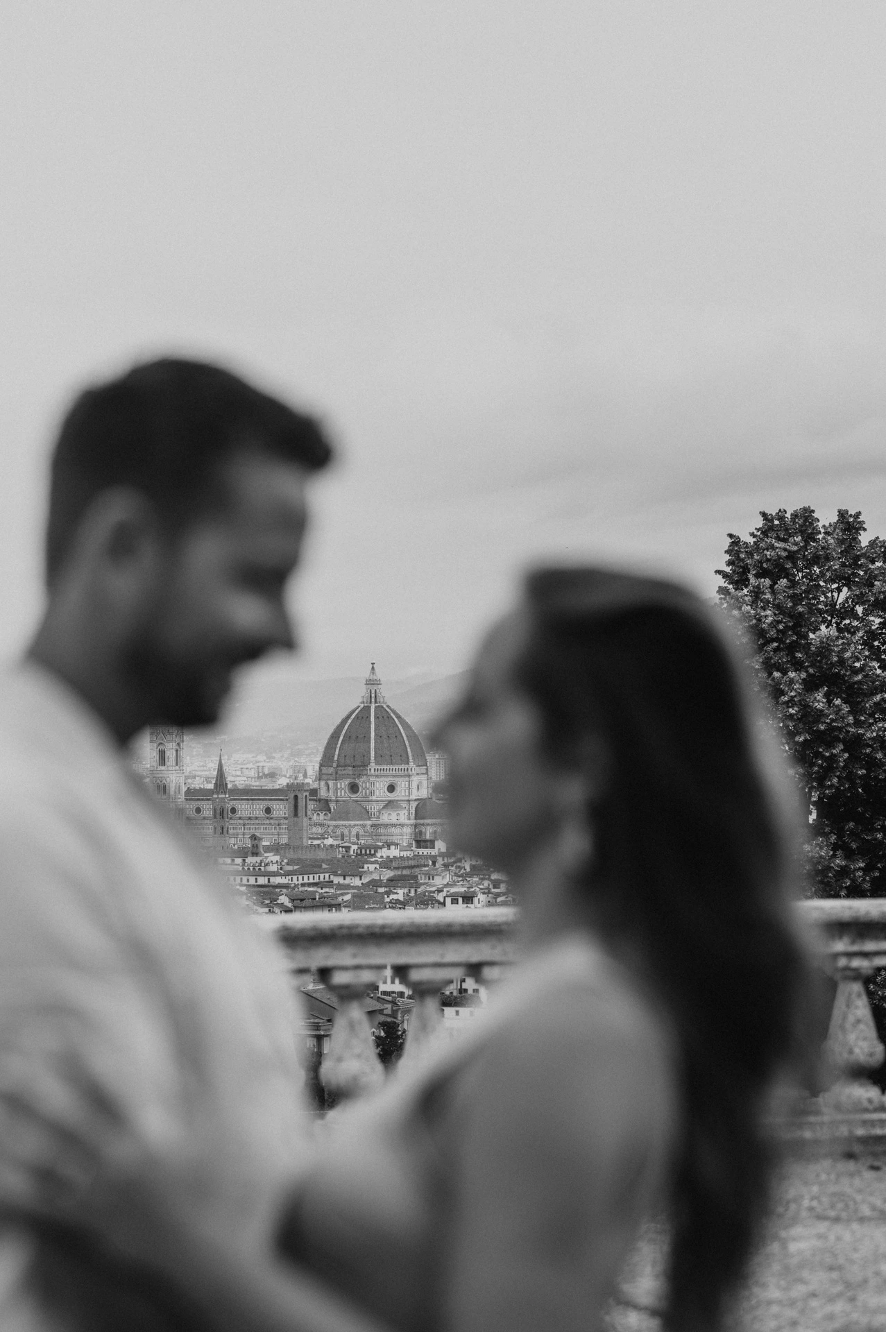 Black-and-white photograph with Florence’s Duomo in focus between the softly blurred couple during their proposal photoshoot.