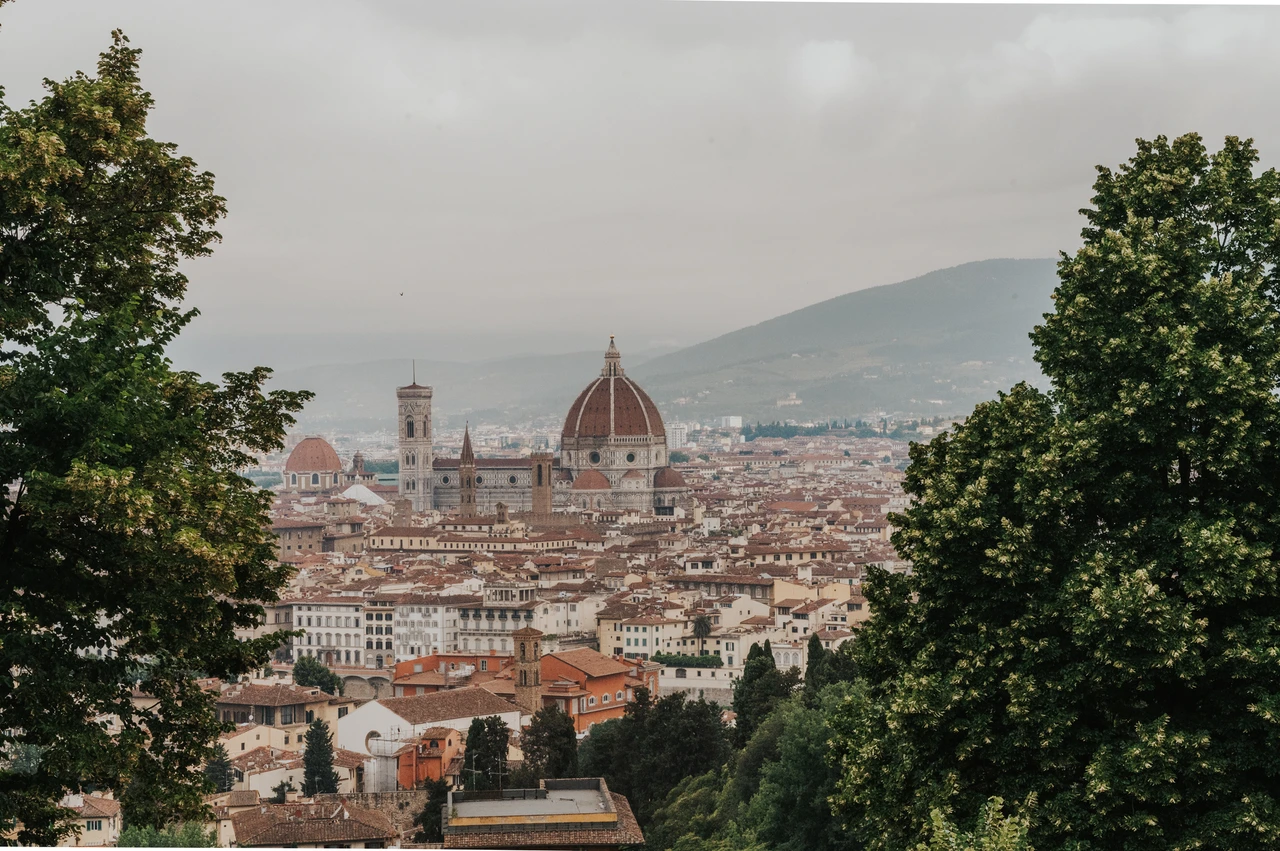 Florence skyline from San Miniato during a proposal photoshoot Florence’s Duomo and red rooftops are framed by trees in a landscape photograph from the proposal photoshoot at San Miniato al Monte.