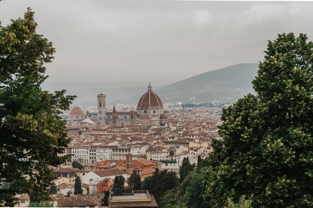 Florence’s Duomo and red rooftops are framed by trees in a landscape photograph from the proposal photoshoot at San Miniato al Monte.