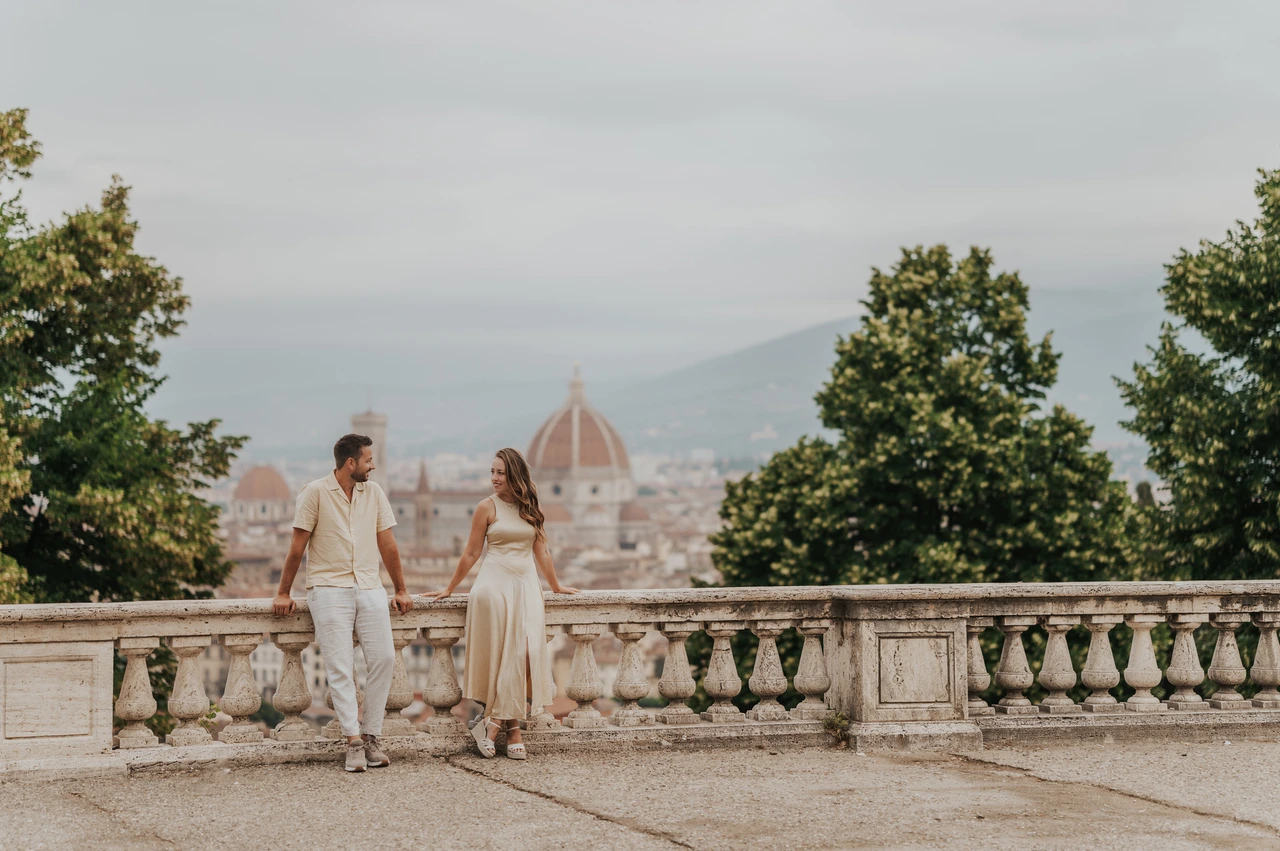 Florence proposal photoshoot beside the viewpoint balustrade The couple stand holding hands beside the viewpoint balustrade with trees and Florence’s Duomo behind them during their proposal photoshoot.