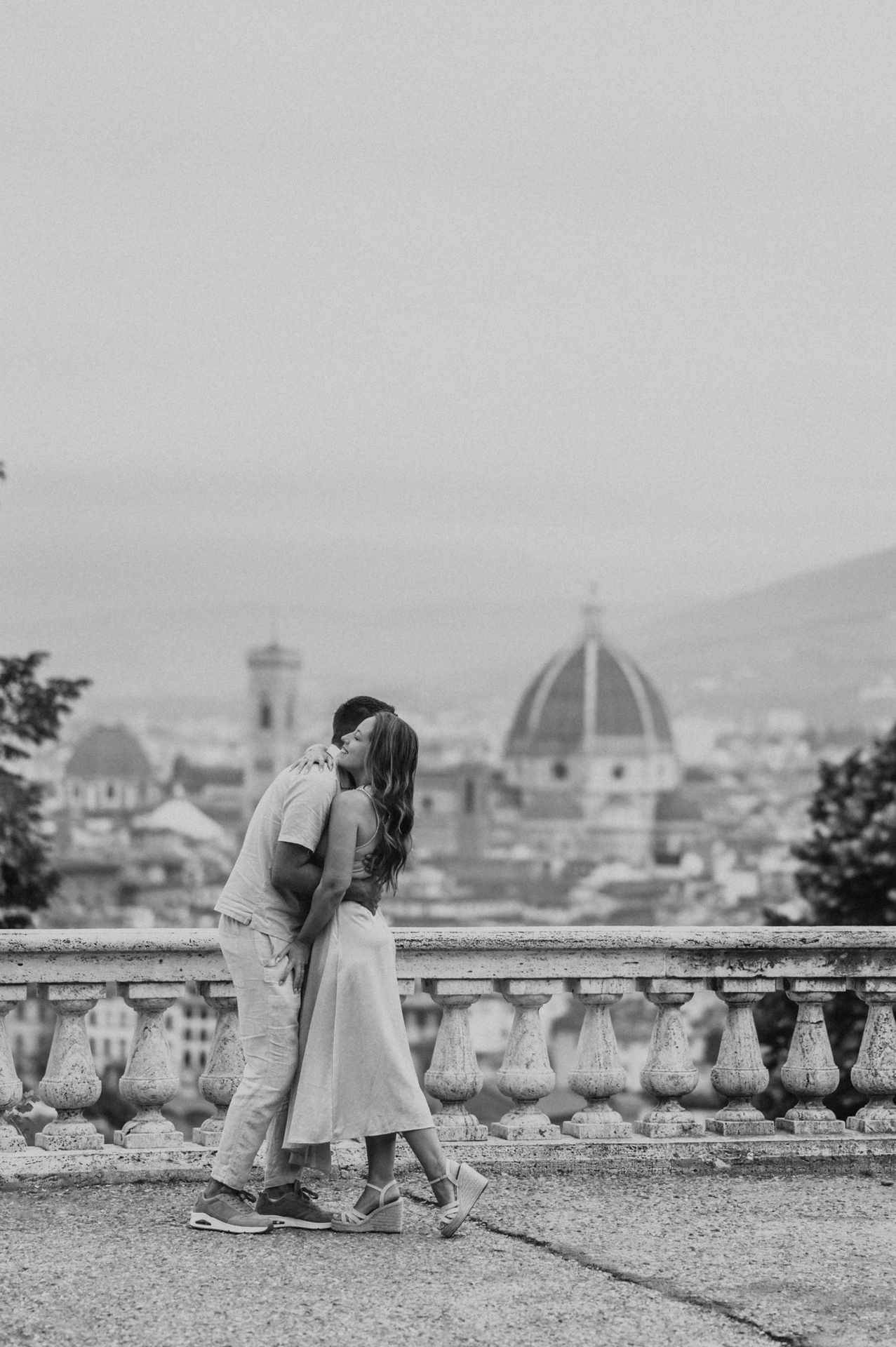 Black-and-white portrait of the couple kissing with Florence’s rooftops behind them during their proposal photoshoot.