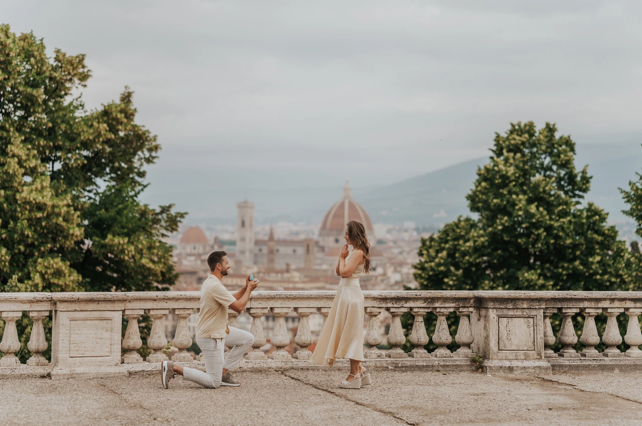 The proposal moment during a Florence photoshoot at San Miniato A wide view of the couple beside San Miniato al Monte’s stone balustrade during their Florence proposal photoshoot, with the Duomo behind them.
