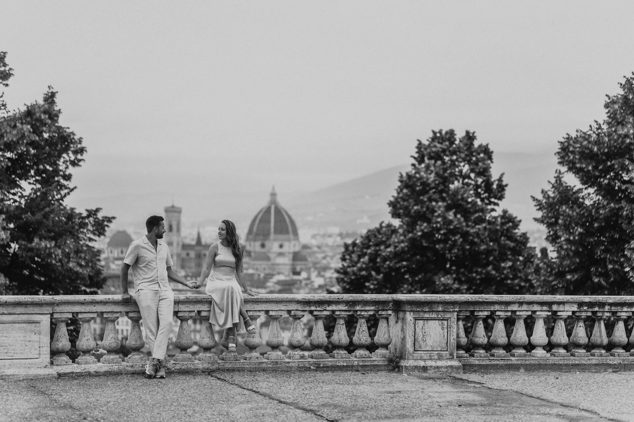 Florence proposal photoshoot with a seated black-and-white portrait Black-and-white view of the couple leaning towards one another beside the balustrade during their Florence proposal photoshoot.