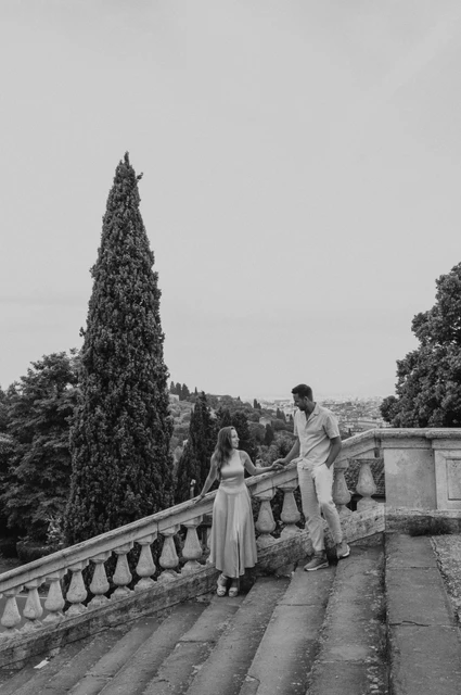 A black-and-white stairway portrait from a Florence proposal photoshoot Black-and-white portrait of the couple on stone steps beneath a tall cypress during their Florence proposal photoshoot.