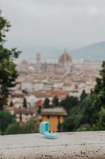 A turquoise ring box rests on a stone ledge above Florence’s rooftops during the proposal photoshoot.