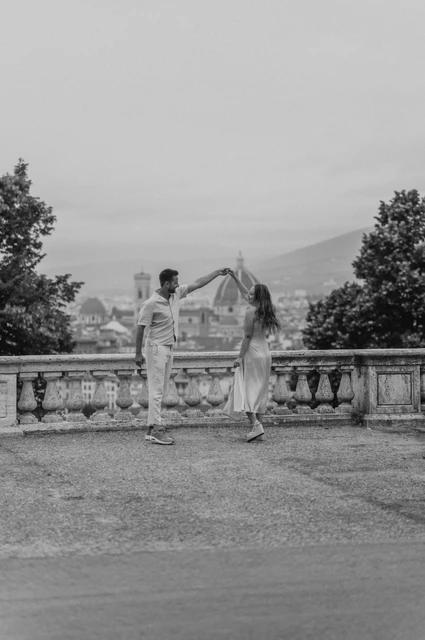 Florence proposal photoshoot with a black-and-white twirl Black-and-white photograph of the couple turning together at the San Miniato viewpoint during their Florence proposal photoshoot.