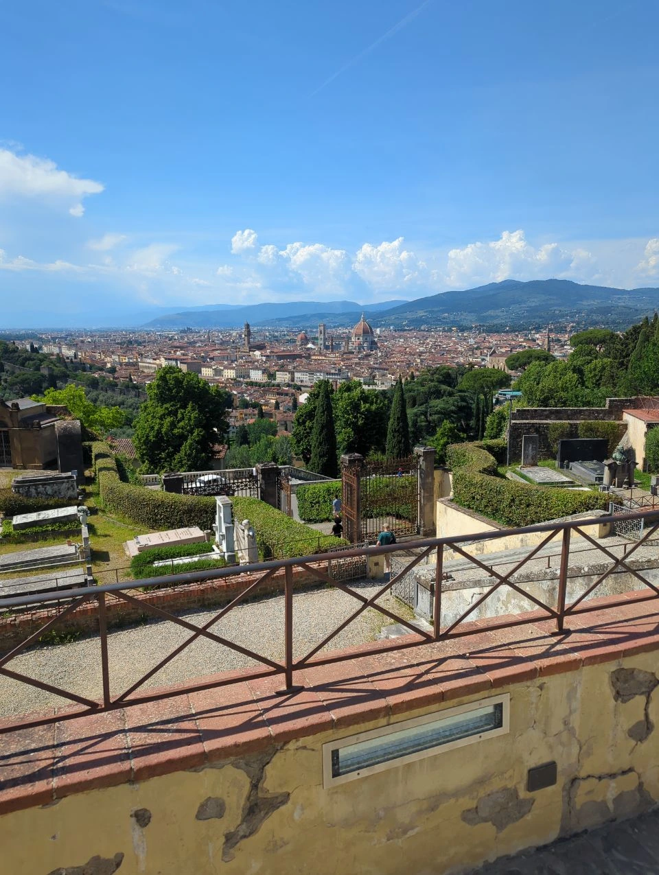 Florence Skyline From the Hills Florence spreads across the valley below a hillside viewpoint, with the cathedral dome and surrounding mountains clearly visible.