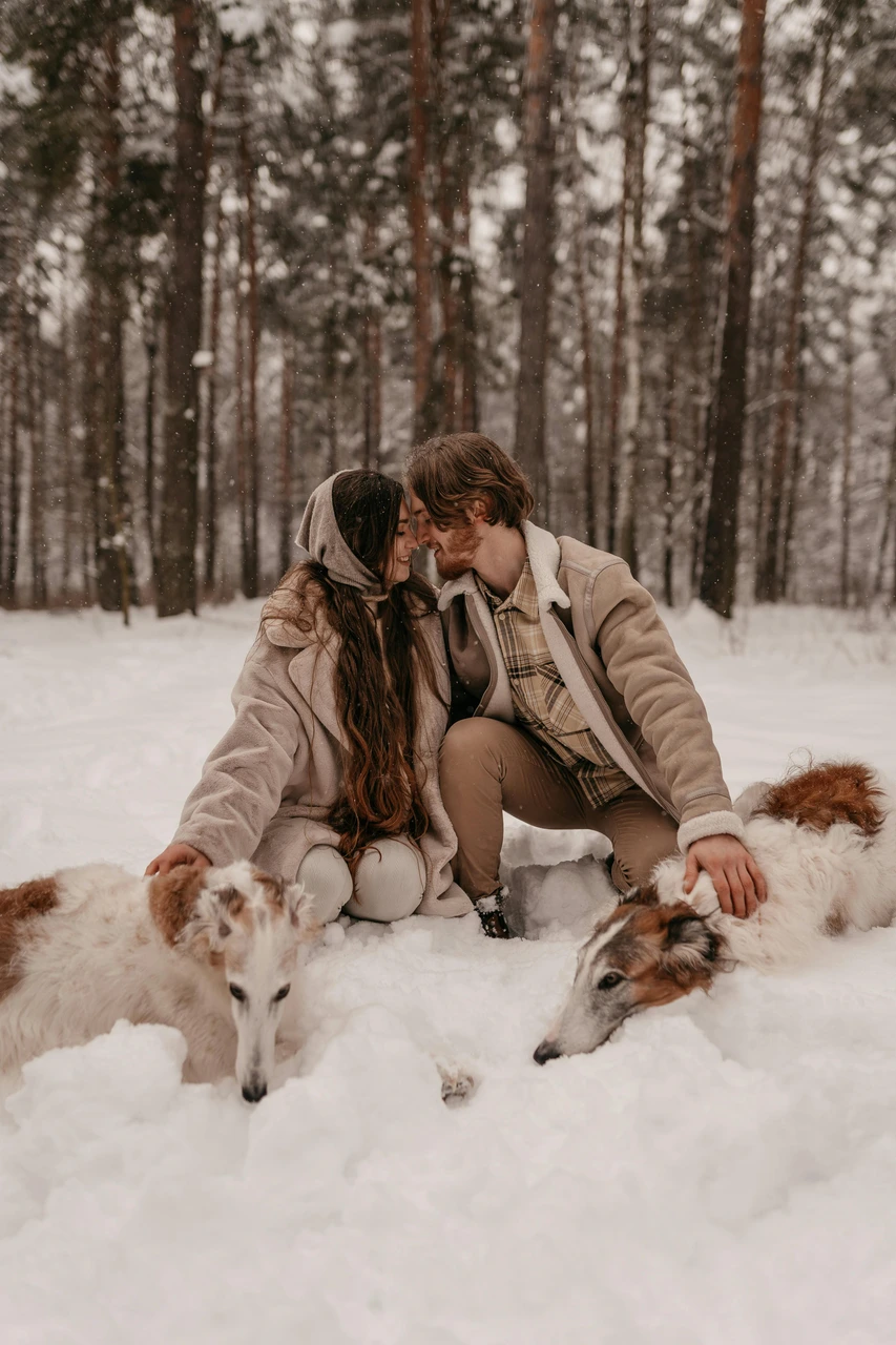 Forest engagement outfits that stand out Couple in layered neutral outfits in snowy forest engagement session