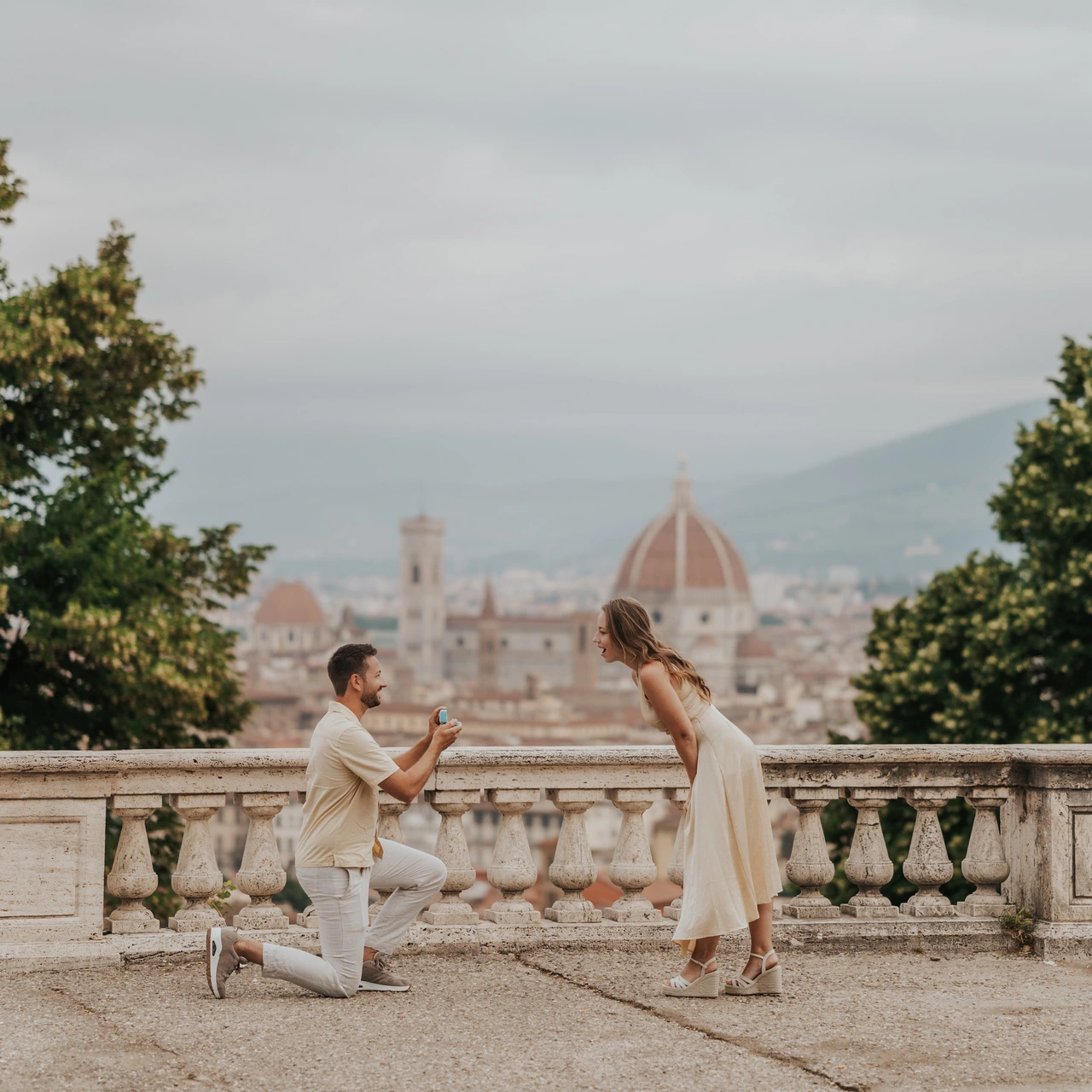 Ein Mann kniet bei einem Heiratsantrag an einer Steinbalustrade, während der Dom das Paar bei diesem Fotoshooting in Florenz umrahmt.
