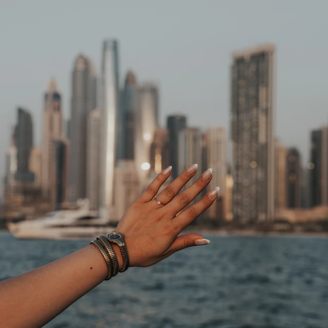 Fotograf für Heiratsanträge Dubai Foto eines Eherings an einer Hand, die von einer Yacht aus vor der Skyline der Dubai Marina gehalten wird – aufgenommen nach einem Heiratsantrag in Dubai.