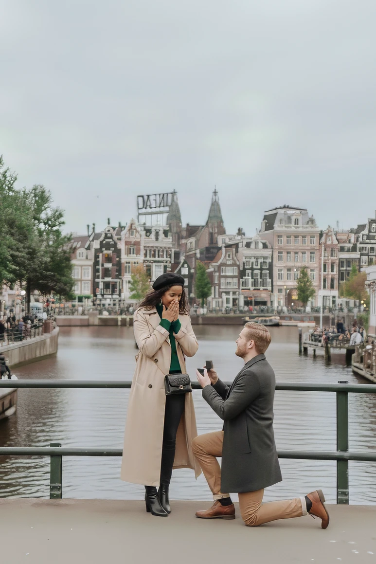 Huwelijksaanzoek op een brug in Amsterdam vastgelegd door een huwelijksaanzoek fotograaf met grachten op de achtergrond