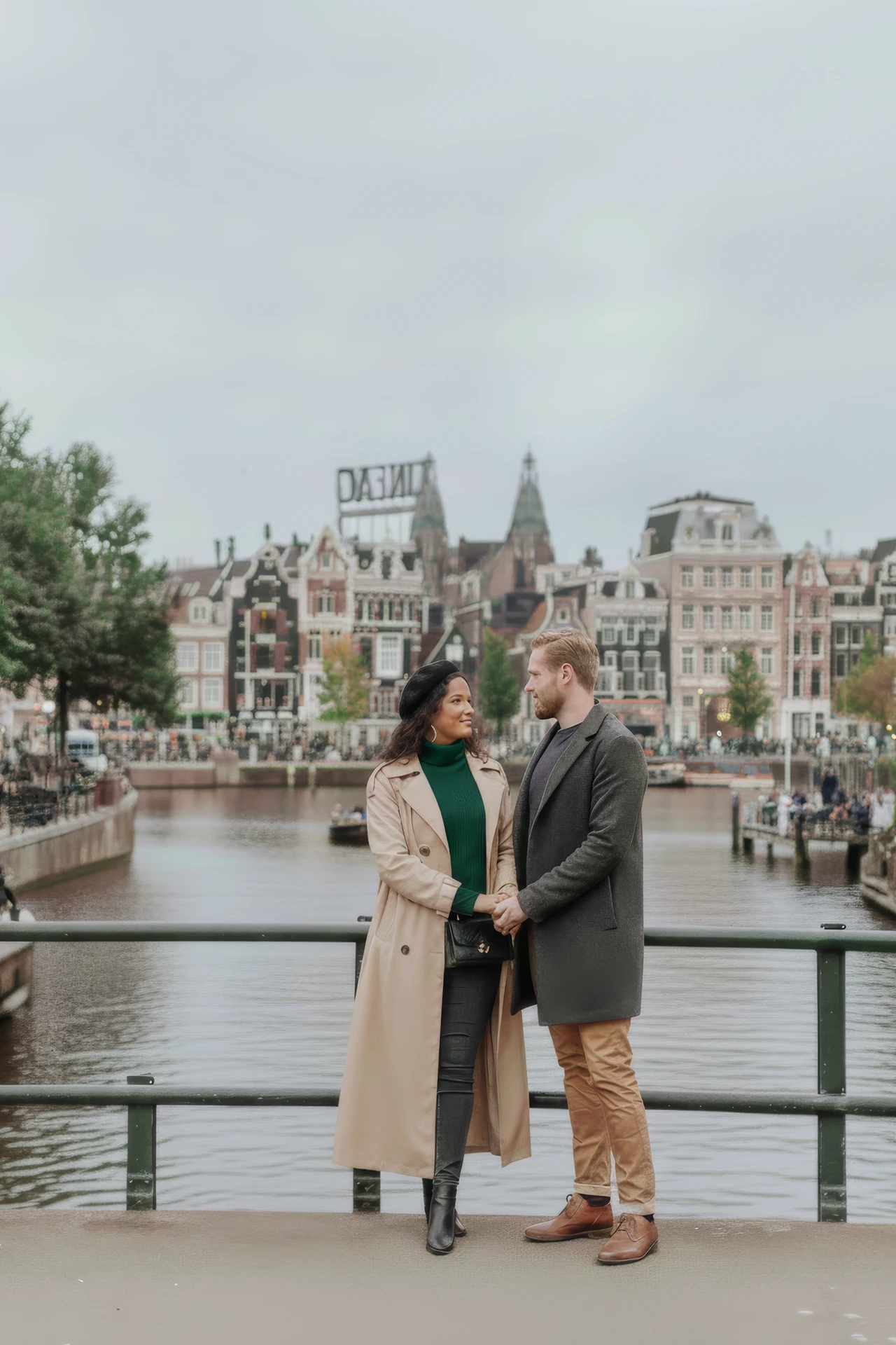 Een koppel fotoshoot op een brug met typische Amsterdamse achtergrond
