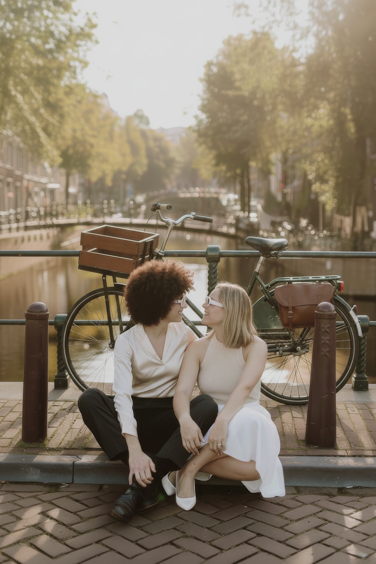 Twee vrouwen die een koppel fotoshoot doen bij een brug over de grachten in Amsterdam