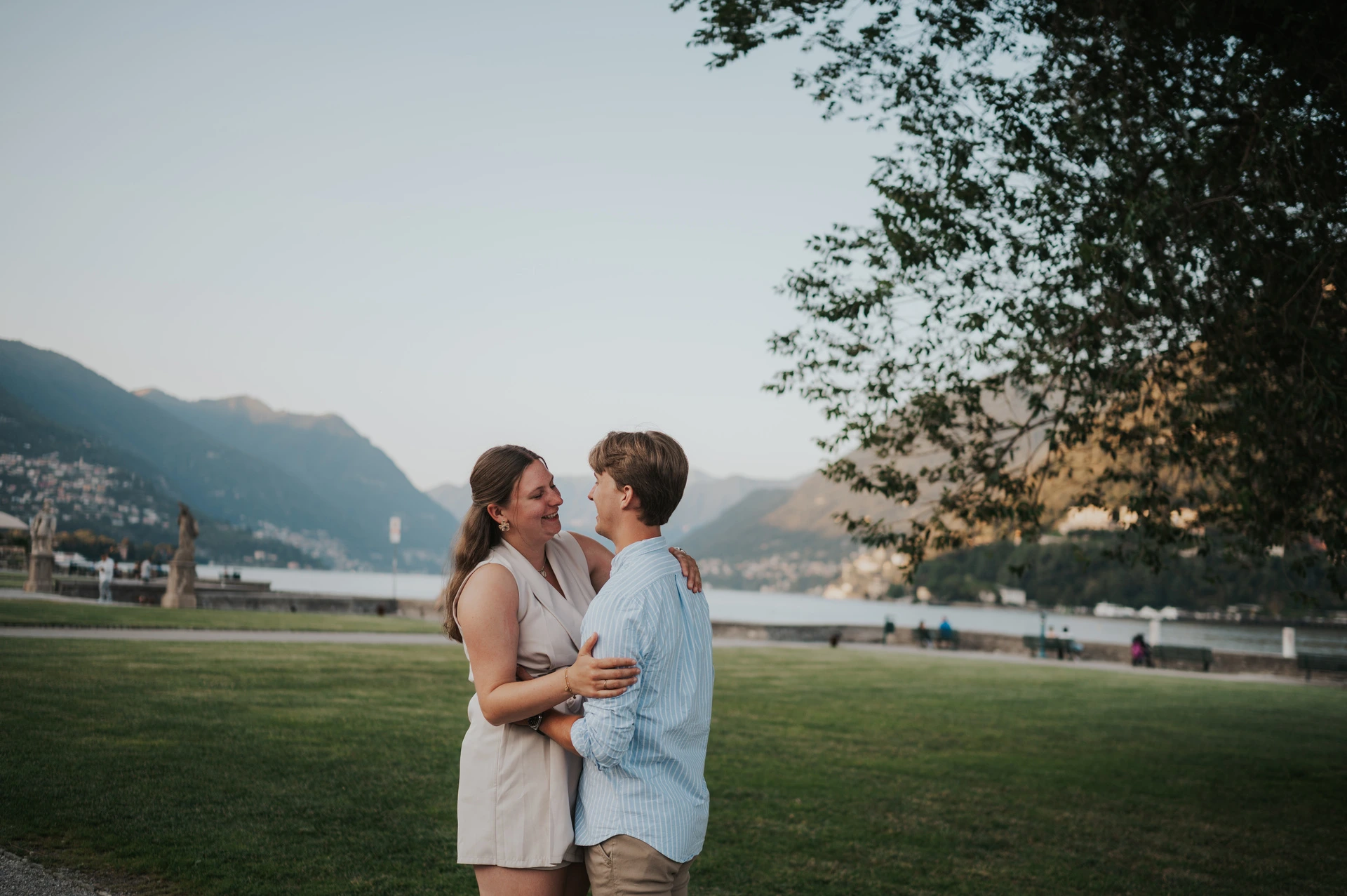 Couple sharing a kiss under a tree on the lakeside lawn during their Lake Como couple photoshoot at Villa Olmo.