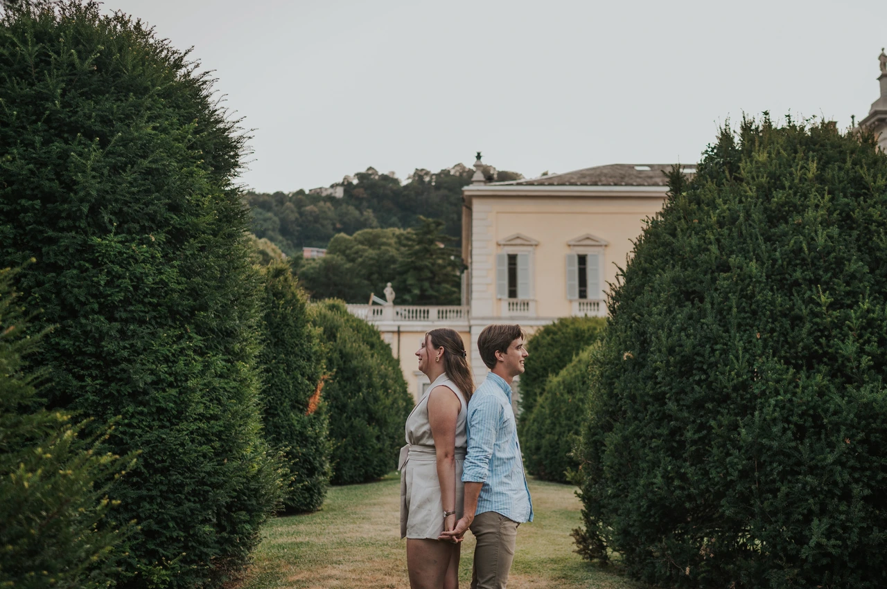 Lake Como couple photoshoot between the villa garden hedges Couple kissing on a garden path between shaped hedges during their Lake Como couple photoshoot at Villa Olmo.