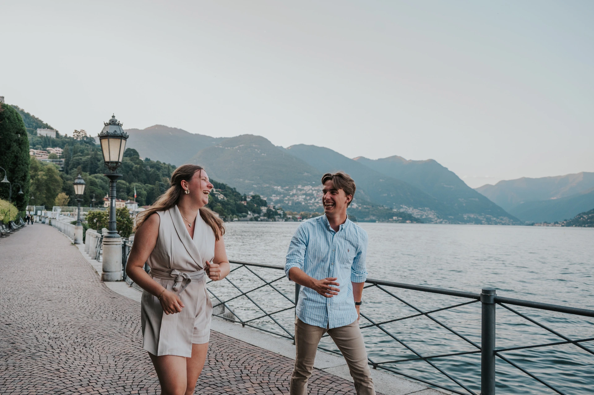 Couple holding hands while walking along the waterfront railing during their Lake Como couple photoshoot in Como.