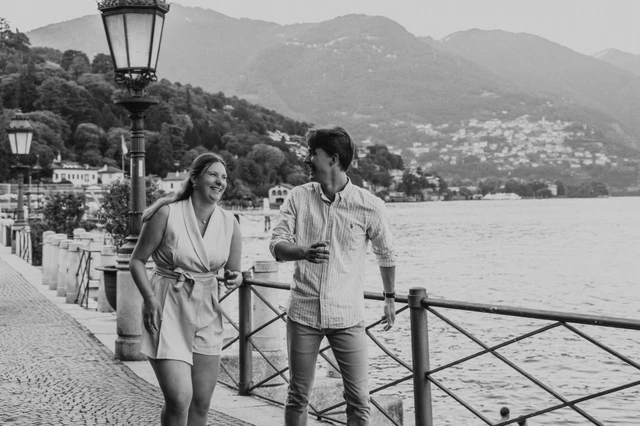 Black-and-white photograph of the couple holding hands on Como’s promenade during their Lake Como couple photoshoot.