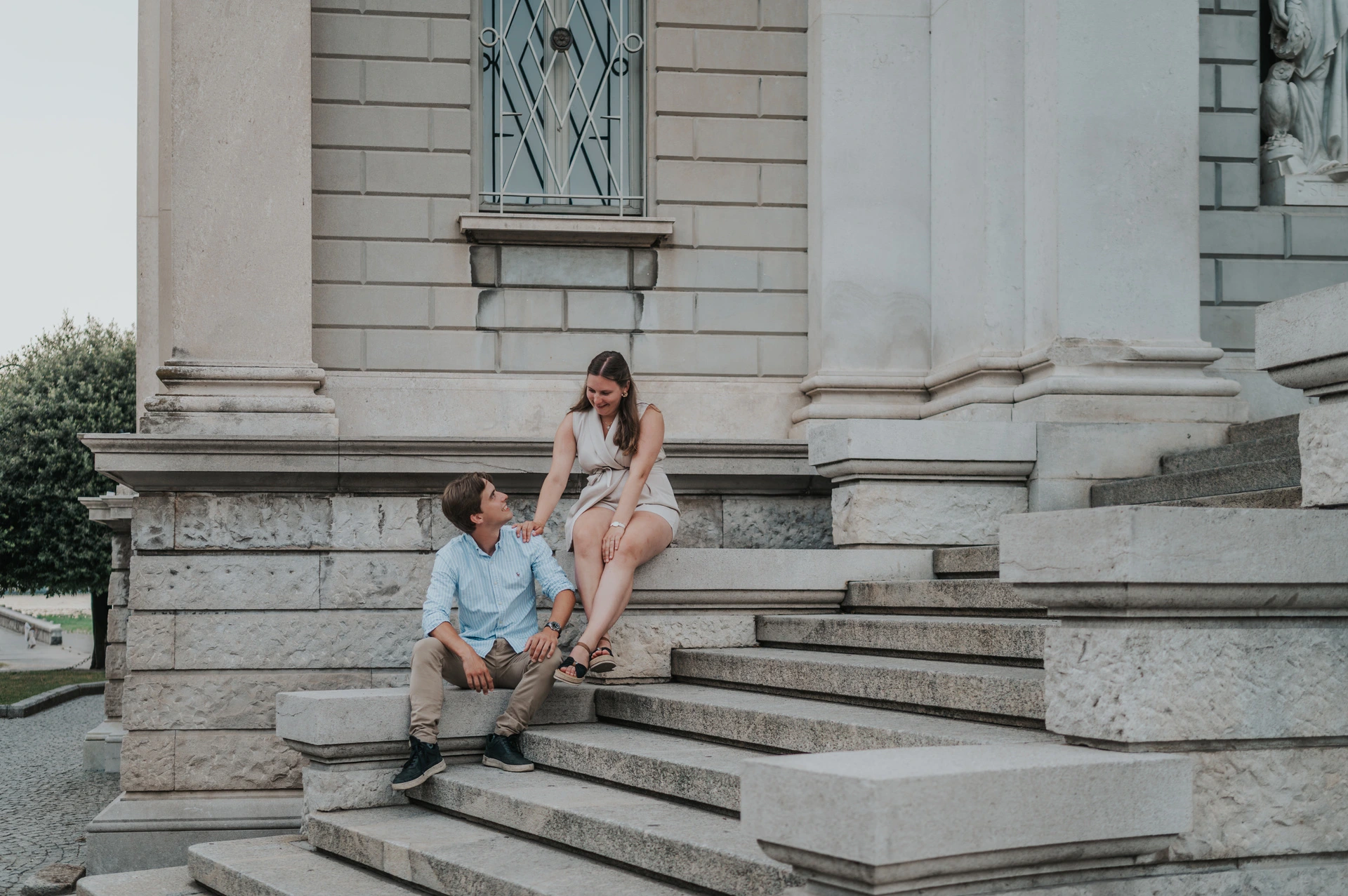 Couple sitting on the stone steps beside Tempio Voltiano’s columns during their Lake Como couple photoshoot.