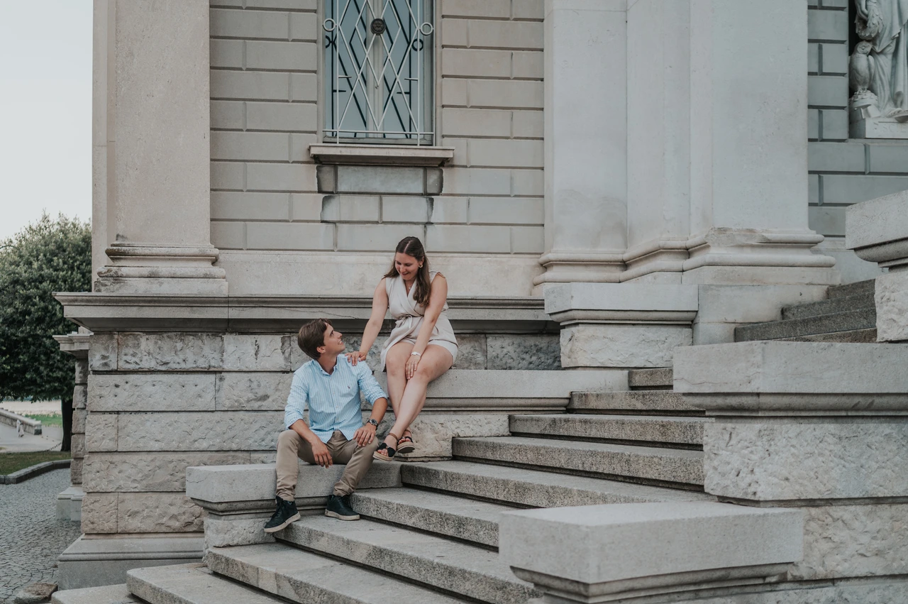 Lake Como couple photoshoot on the steps of Tempio Voltiano Couple sitting on the stone steps beside Tempio Voltiano’s columns during their Lake Como couple photoshoot.