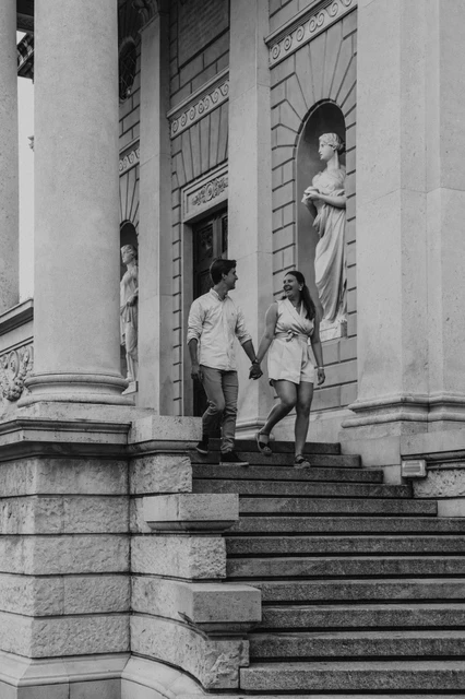 Lake Como couple photoshoot on Tempio Voltiano’s stairs in black and white Black-and-white photograph of the couple walking down the column-lined steps of Tempio Voltiano during their Lake Como couple photoshoot.