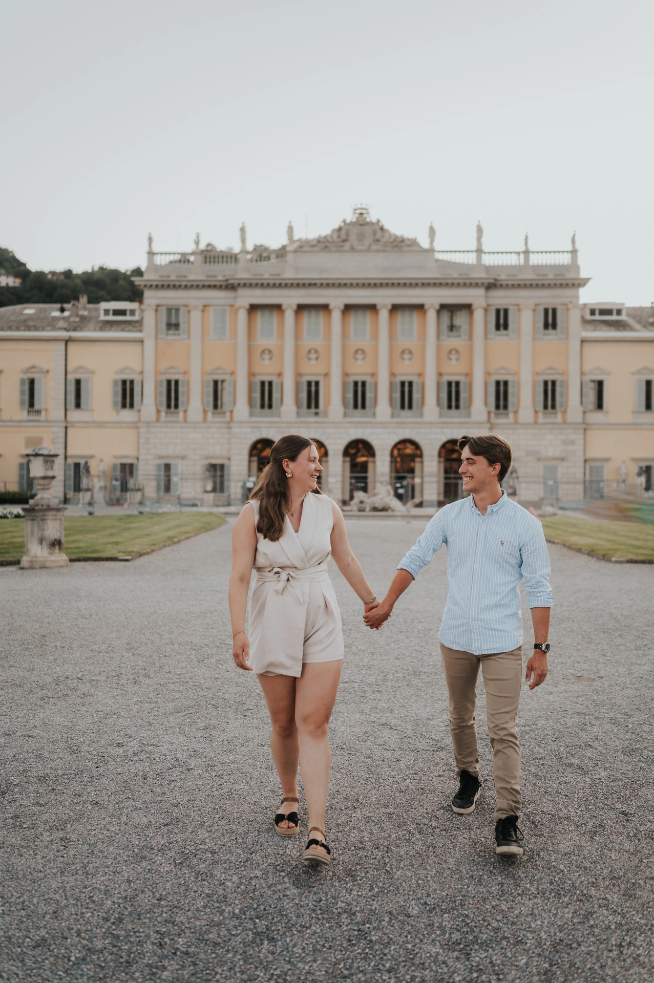 Couple walking hand in hand with Villa Olmo’s pale facade behind them during their Lake Como couple photoshoot in Como.