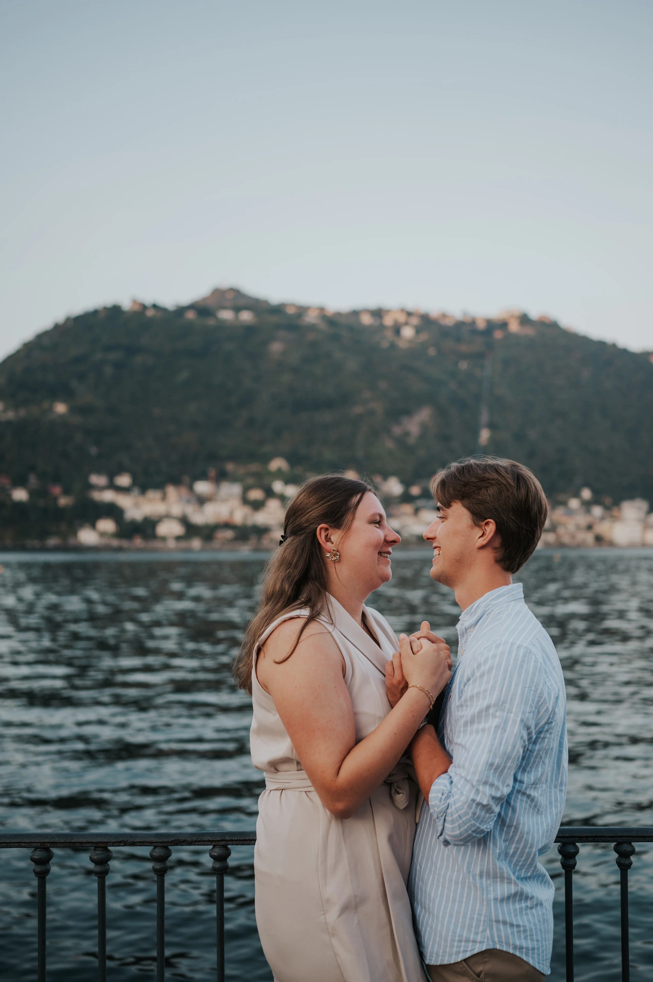 Couple smiling at each other beside the waterfront railing during their Lake Como couple photoshoot in Como.