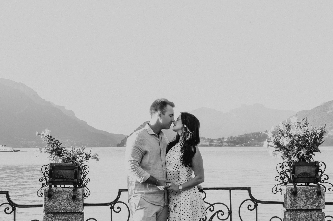 Black-and-white Lake Como photoshoot between the Menaggio flowers Black-and-white portrait of the couple holding each other between flower-filled pillars during their Lake Como photoshoot in Menaggio.