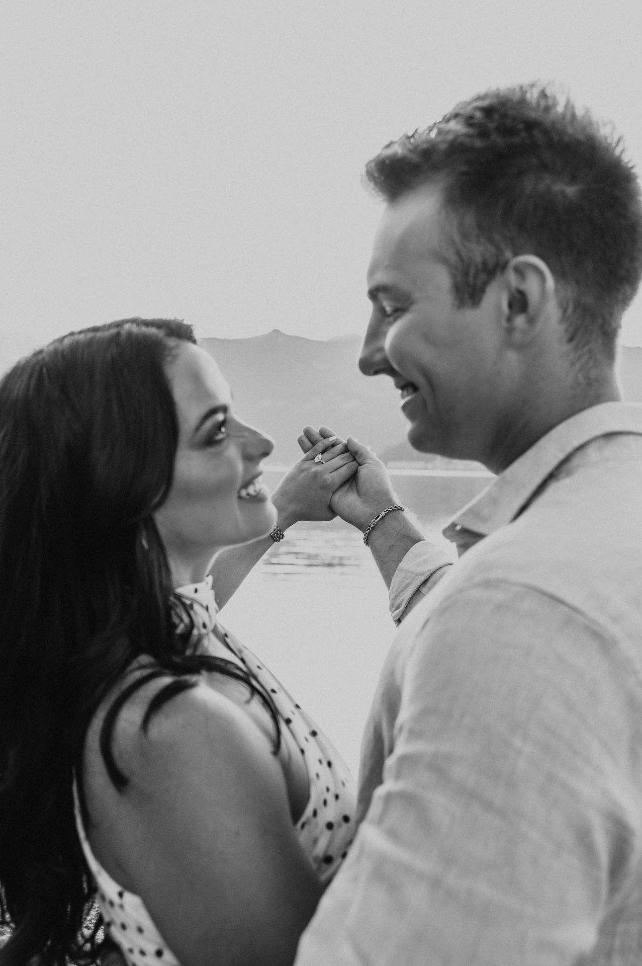 Black-and-white close portrait of the couple looking at each other beside their raised hands during their Lake Como photoshoot.