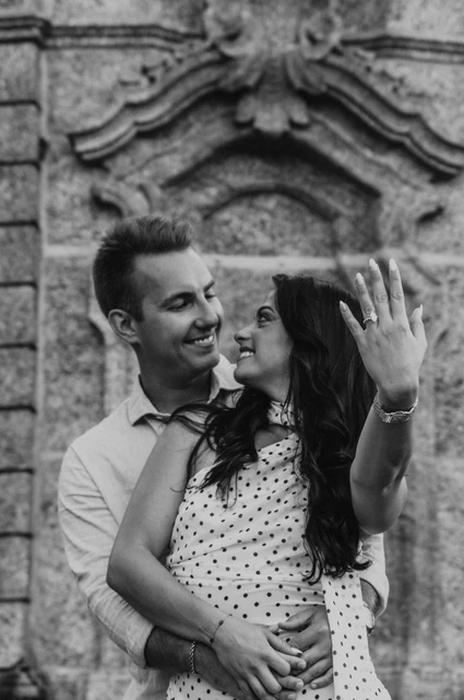 Black-and-white Lake Como photoshoot showing the engagement ring Black-and-white close portrait of the couple displaying her engagement ring against decorative stonework during their Lake Como photoshoot.