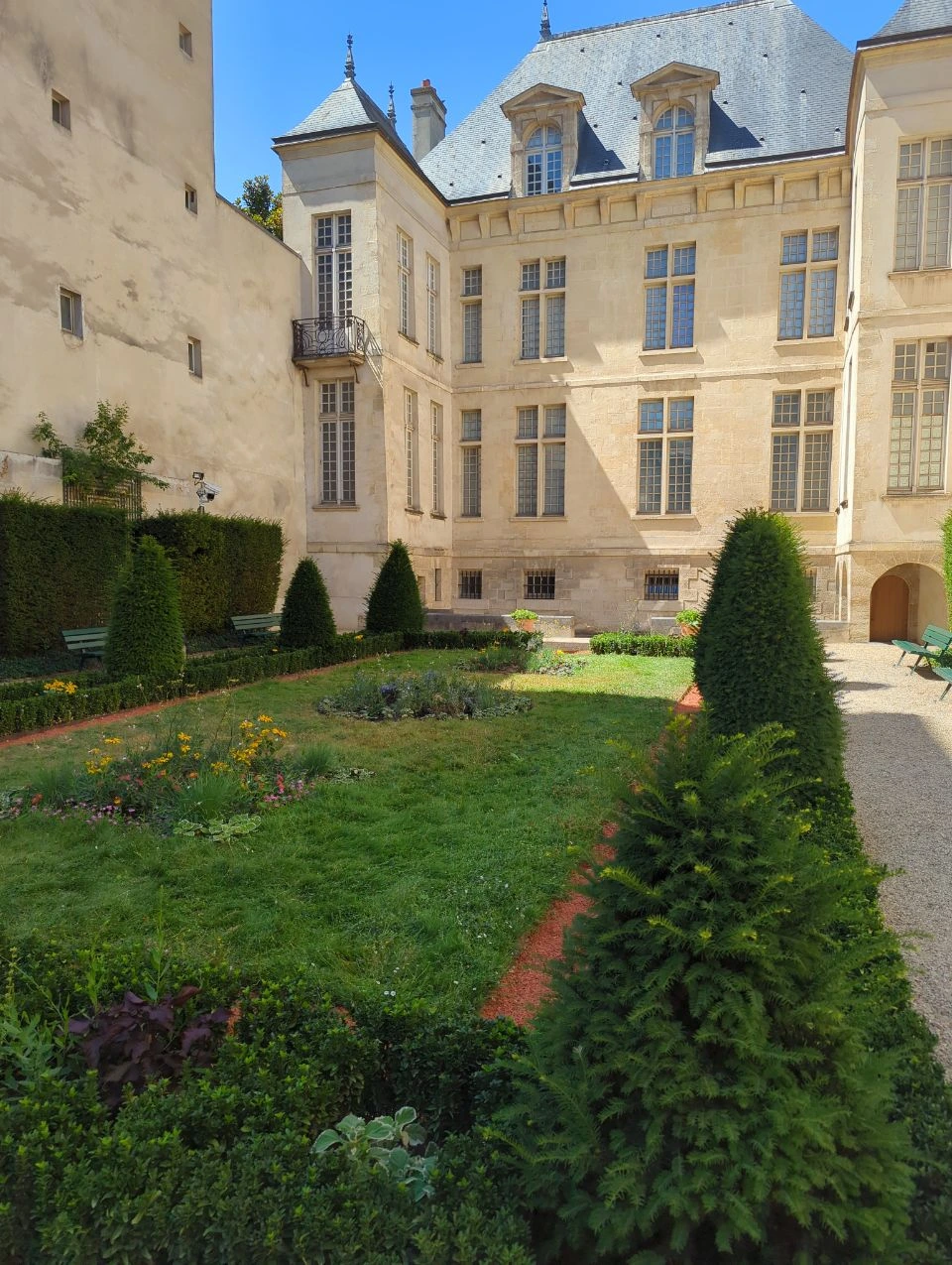 Paris Photoshoot - Le Marais Pocket Garden A compact formal garden and pale historic façade form a quiet courtyard setting in Le Marais for a carefully planned Paris photoshoot.