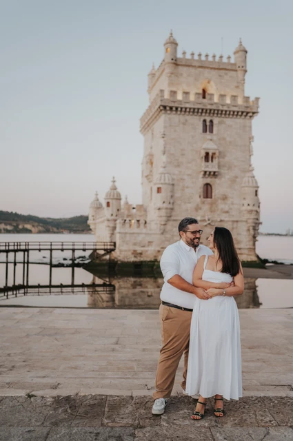 A full-length tower embrace | Lisbon anniversary photoshoot The couple holding each other in a full-length portrait by Belém Tower during their anniversary photoshoot in Lisbon.