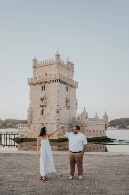 Raised hands beside Belém Tower | Lisbon anniversary photoshoot The couple raising their joined hands between them in front of Belém Tower during their anniversary photoshoot in Lisbon.