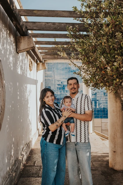 A family portrait beneath the pergola | Lisbon family photoshoot The parents holding their baby beneath the pergola at Miradouro de Santa Luzia during their family photoshoot in Lisbon.