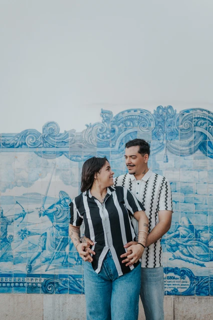 A close portrait of the parents together | Lisbon family photoshoot The parents smiling at each other in a close embrace against the blue tile panel during their family photoshoot in Lisbon.