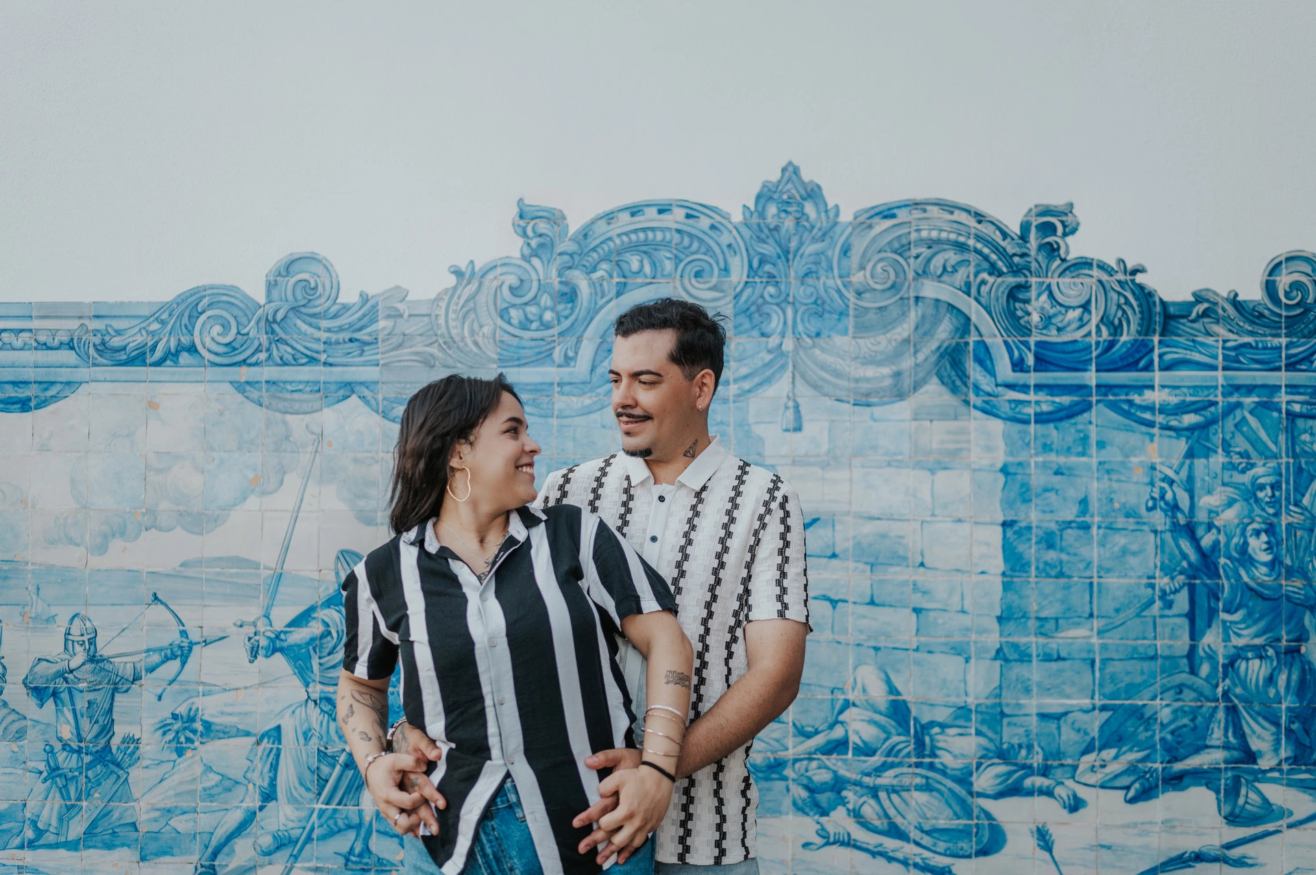 A close portrait of the parents together | Lisbon family photoshoot The parents smiling at each other in a close embrace against the blue tile panel during their family photoshoot in Lisbon.