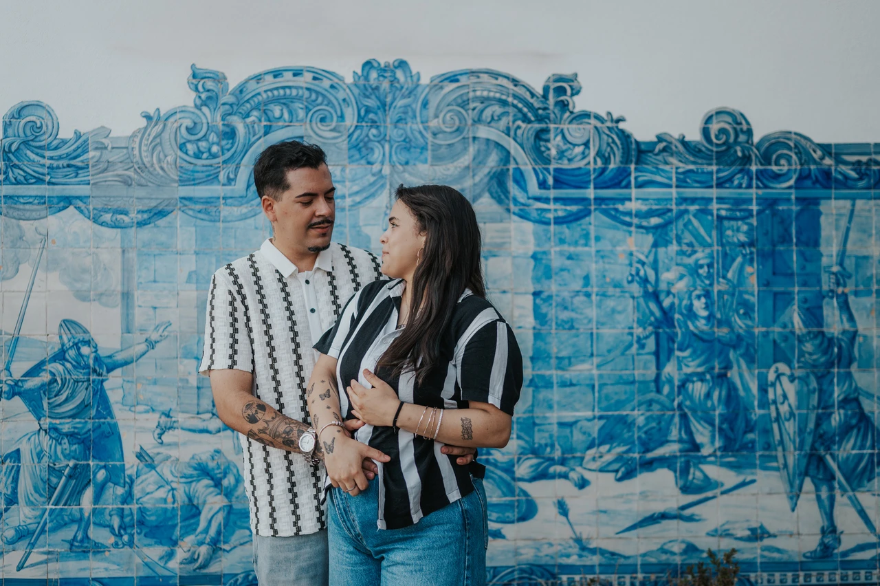 A shared glance beside the blue tiles | Lisbon family photoshoot The parents facing each other with their hands joined in front of the blue tile panel during their family photoshoot in Lisbon.