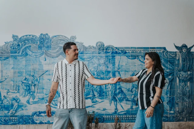 The parents reaching towards each other with their hands joined beside the blue tiles during their family photoshoot in Lisbon.