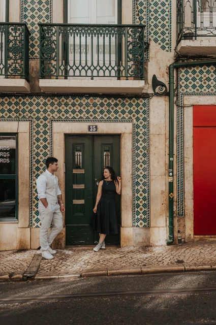 A portrait at the green tiled doorway | Lisbon couple photoshoot The couple standing apart beside a green door surrounded by patterned tiles during their couple photoshoot in Lisbon.