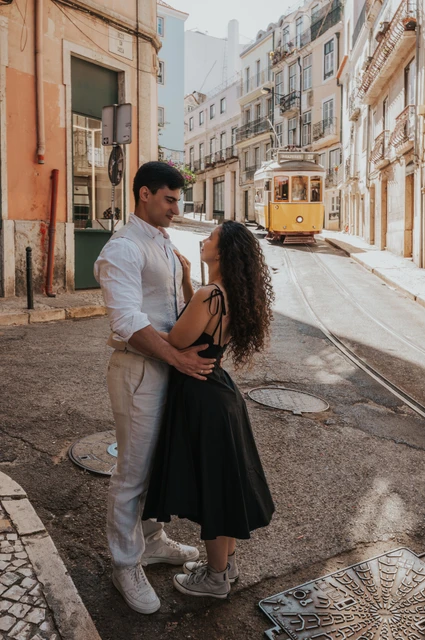 An embrace on the old street | Lisbon couple photoshoot The couple embracing beside the street with the yellow funicular farther behind them during their couple photoshoot in Lisbon.